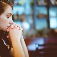 a woman with her eyes closed and hands folded in prayer