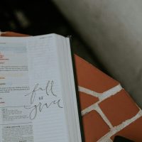 A bible book with a black pen on it with writing that says full of grace. Bible verses about Grace.